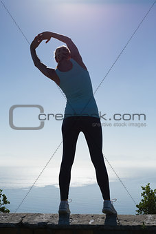 Fit woman stretching her arms looking out to sea