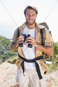Handsome hiker holding binoculars on mountain trail