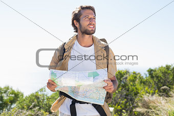 Handsome hiker holding map on mountain trail