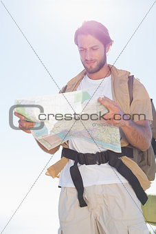 Handsome hiker reading map on mountain trail