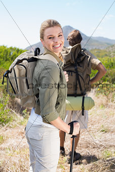 Attractive hiking couple walking on mountain trail woman smiling at camera