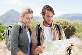Attractive hiking couple reading the map on mountain trail