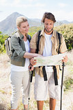 Attractive hiking couple reading the map on mountain trail