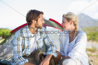 Attractive hiking couple smiling at each other outside their tent