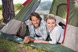 Attractive couple lying in their tent smiling at camera