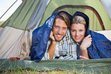Attractive couple lying in their tent smiling at camera