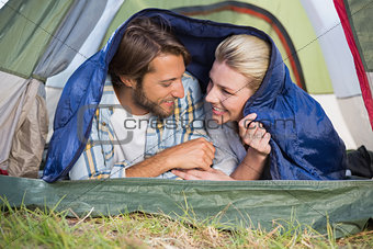 Attractive couple lying in their tent smiling at each other