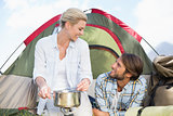Attractive happy couple cooking on camping stove