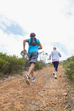 Fit attractive couple jogging up mountain trail