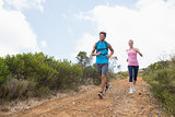 Fit attractive couple jogging down mountain trail