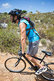 Fit man cycling up mountain trail
