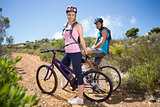 Fit couple cycling up mountain trail smiling