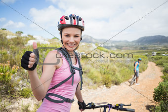 Fit couple cycling on mountain trail woman smiling at camera