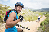 Fit couple cycling on mountain trail man smiling at camera