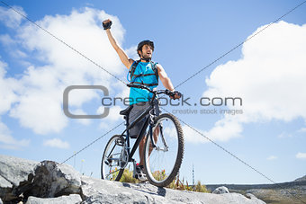 Fit man cycling on rocky terrain and cheering