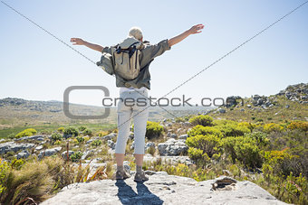 Hiker standing at the summit with her arms out