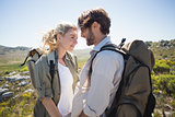 Hiking couple standing on mountain terrain smiling at each other