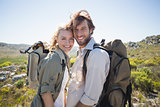 Hiking couple standing on mountain terrain smiling at camera