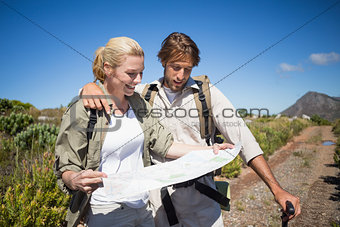 Hiking couple walking on mountain terrain looking at map