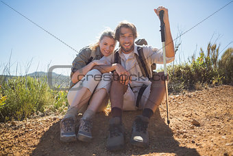 Hiking couple taking a break on mountain terrain smiling at camera