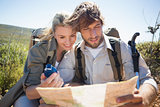 Hiking couple taking a break on mountain terrain using map and compass