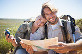 Hiking couple taking a break on mountain terrain using map and compass