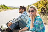 Attractive couple sitting on the road hitch hiking