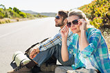 Attractive couple sitting on the road hitch hiking