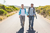 Attractive couple standing on the road holding hands smiling at camera