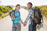 Attractive couple standing on the road holding hands smiling at camera
