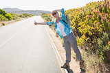 Attractive blonde hitch hiking on rural road