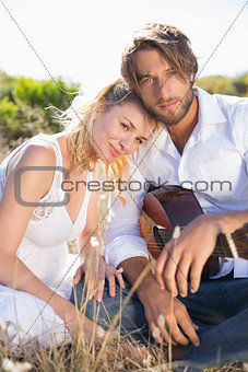 Handsome man serenading his girlfriend with guitar smiling at camera