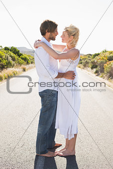 Attractive couple embracing barefoot on the road