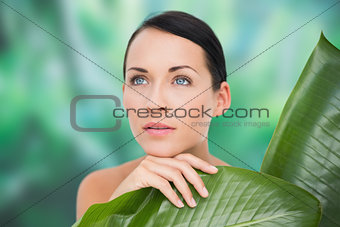 Beautiful nude brunette posing with green leaves