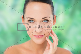 Beautiful nude brunette applying face cream