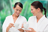 Beautiful friends in bathrobes drinking herbal tea