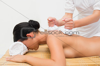 Beautiful brunette enjoying a herbal compress massage