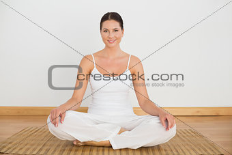 Smiling brunette sitting in lotus pose looking at camera