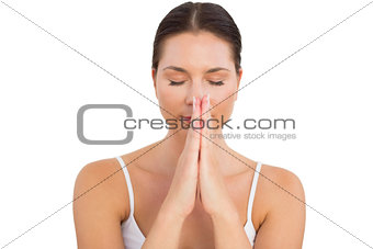 Peaceful brunette meditating with hands together