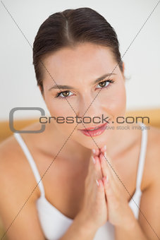 Smiling brunette meditating with hands together