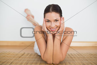 Smiling brunette lying on floor looking at camera