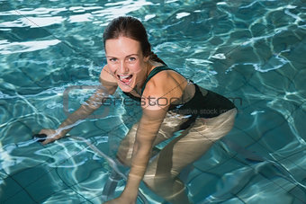 Fit happy brunette using underwater exercise bike