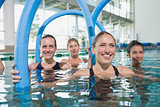 Female fitness class doing aqua aerobics with foam rollers