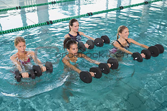 Female fitness class doing aqua aerobics with foam dumbbells
