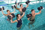 Happy fitness class doing aqua aerobics with foam dumbbells