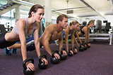 Fitness class in plank position with kettlebells