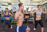 Fitness class lifting barbells together