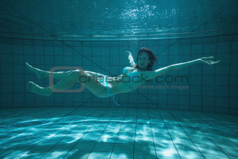 Pretty swimmer looking at camera underwater in bikini