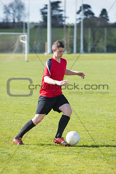 Football player in red playing on pitch