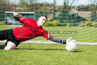 Goalkeeper in red saving a goal during a game